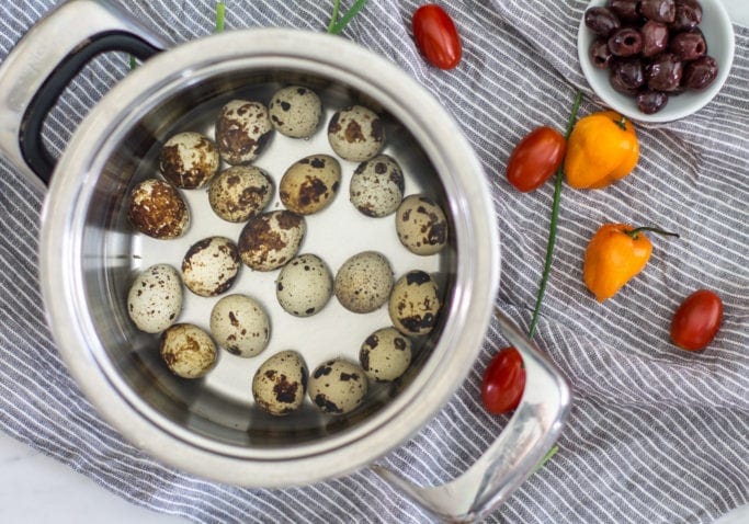 Quail eggs in a pot of water. Cherry tomatoes, habañero peppers, stripe towel