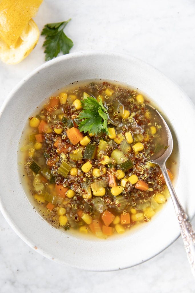 Bowl of red quinoa soup with corn, zucchini, carrots,