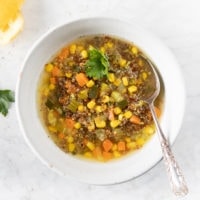 Bowl of red quinoa soup with corn, zucchini, carrots,