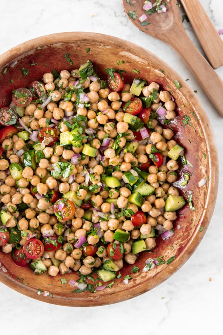 Wooden bowl and salad utensils with Easy Chickpea Salad With Tomatoes and Cucumbers