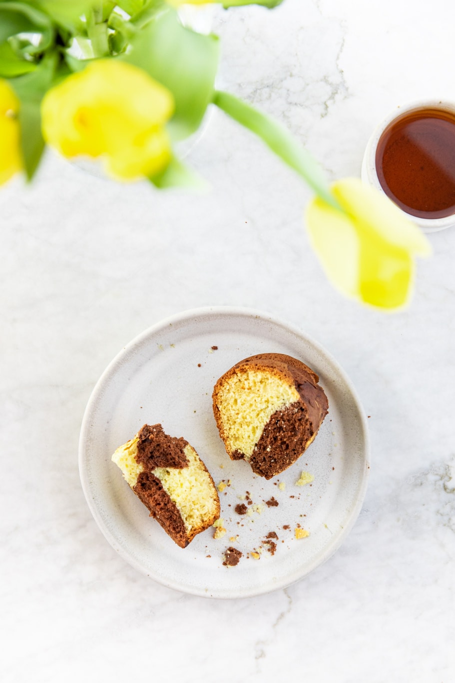 Slices of Vanilla Chocolate Marble Bundt Cake with cup of tea and vase of yellow tulips