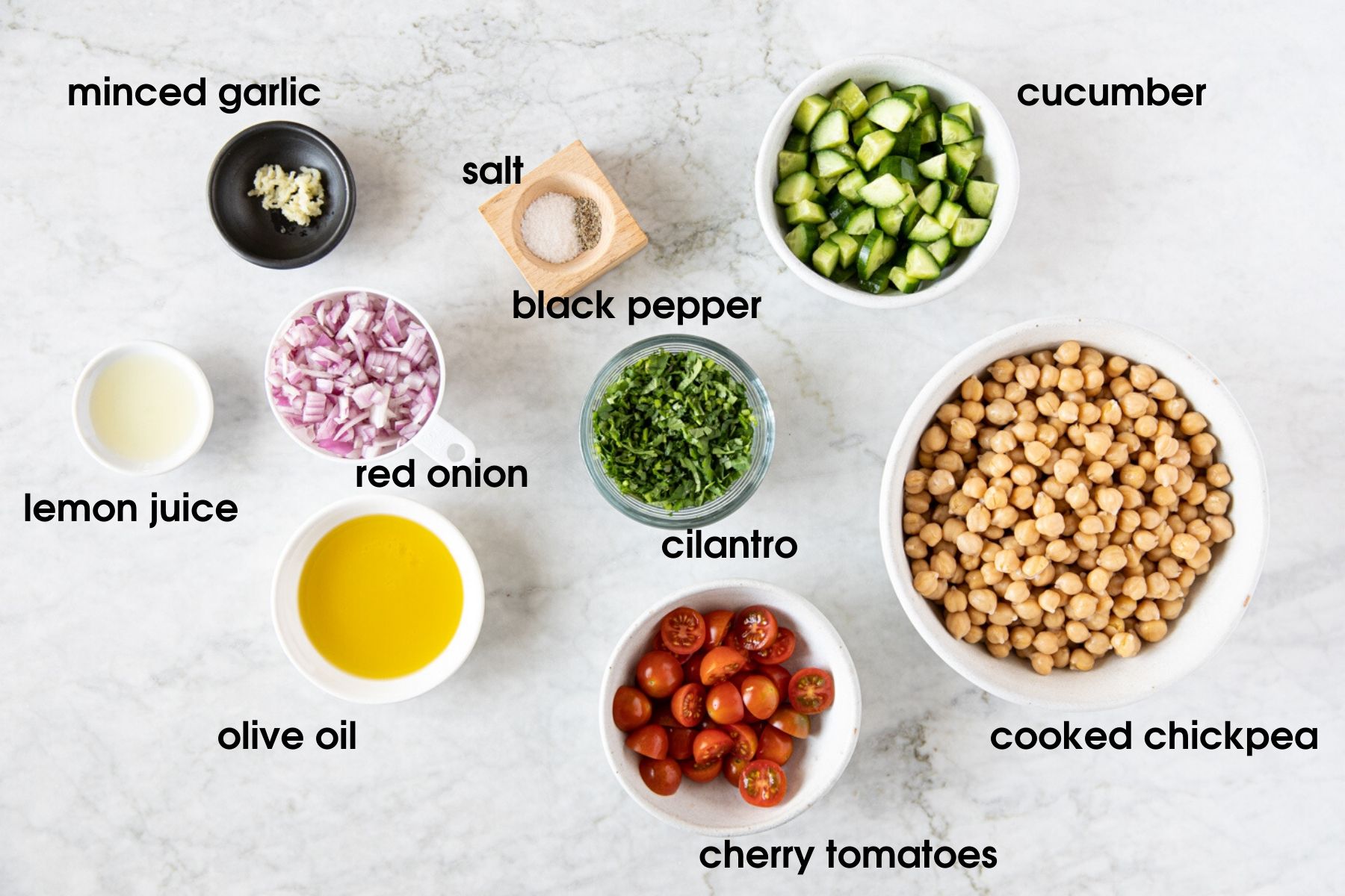 All ingredients for Easy Chickpea Salad With Tomatoes and Cucumbers: minced garlic, salt, black pepper, cucumber, lemon juice, red onion, cilantro, chickpea, olive oil, and cherry tomatoes