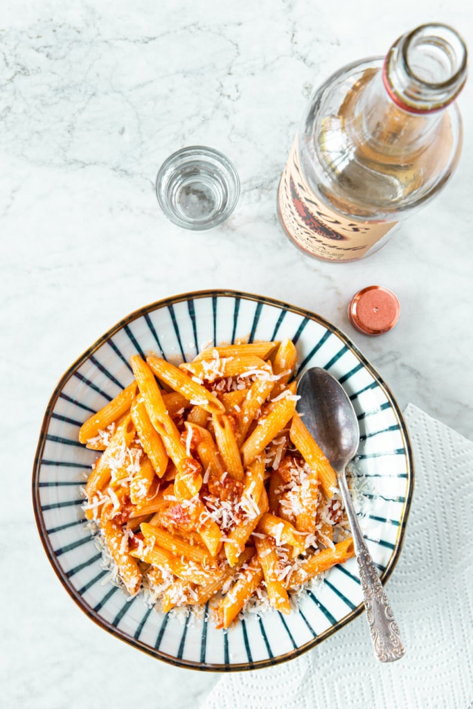 Plate with Easy Creamy Penne Alla Vodka Recipe, with a spoon, and grated parmesan cheese