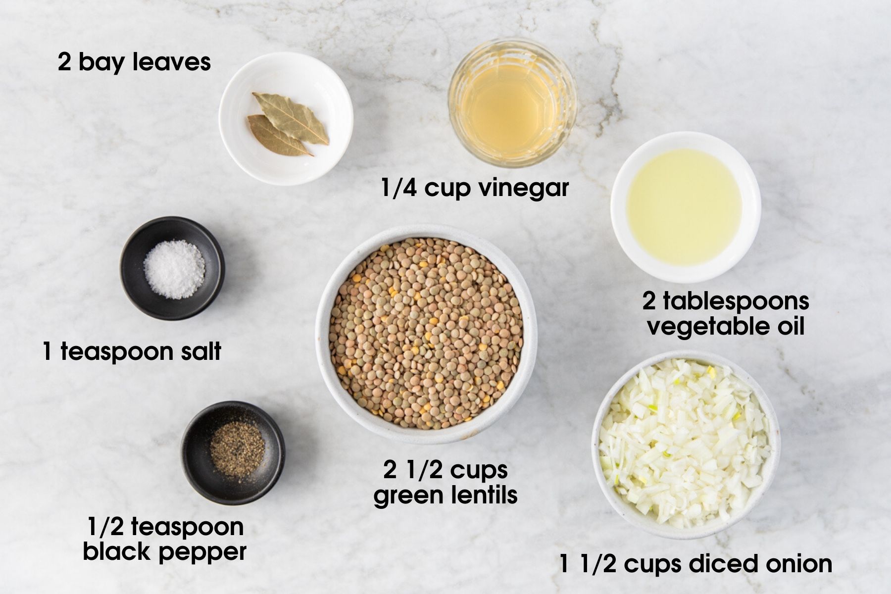Ingredients for sweet sour one-pot green lentils: bay leaves, vinegar, vegetable oil, onion, green lentils, black pepper, and salt