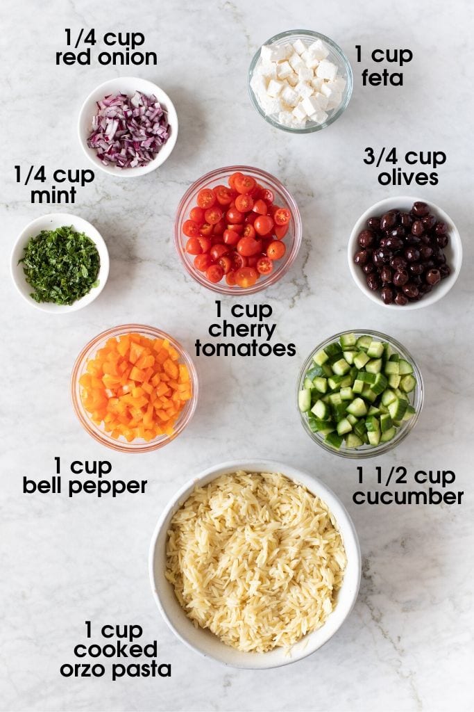 Ingredients to make 15-Minute Orzo Pasta Salad including red onion, feta, mint, olives, tomatoes, bell peppers, cucumbers and cooked orzo pasta
