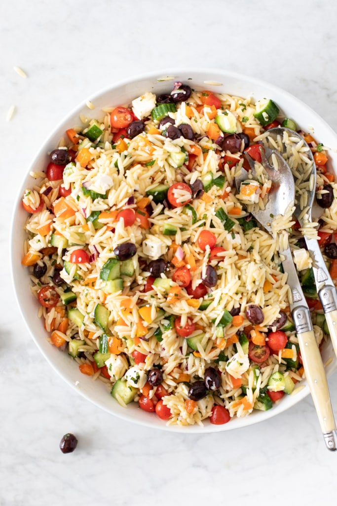 Bowl and serving utensils with 15-Minute Orzo Pasta Salad